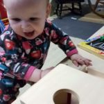 girl baby using object permanence box