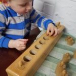 boy using montessori cylinder block